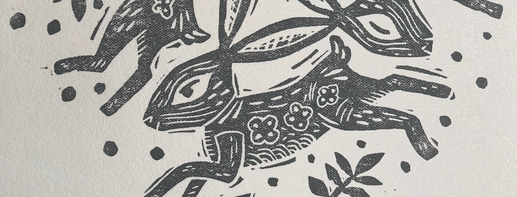 Black and white linocut print of hares with floral patterns on a light gray background