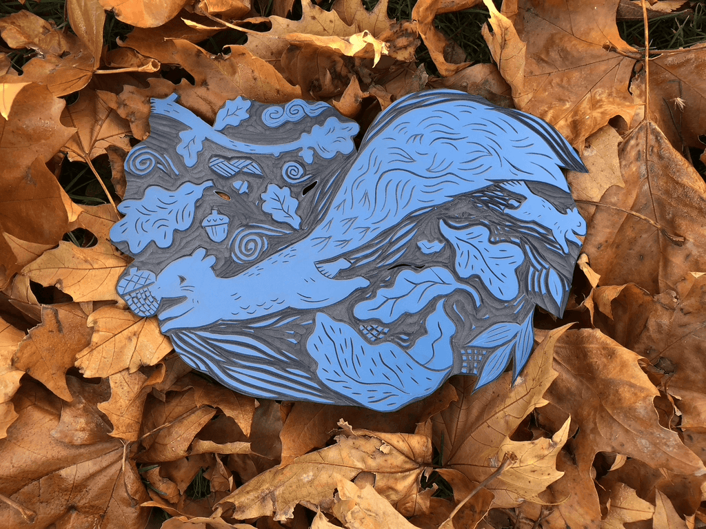decorative linocut block with nature design on a bed of brown leaves